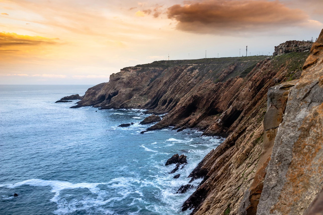 cliffs and caves along ocean with clouds